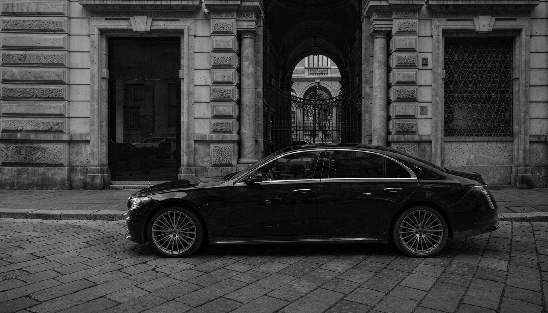 foto di macchina mercedes nera parcheggiata davanti a un edificio antico